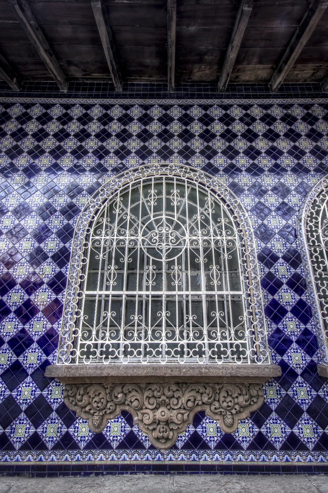 Ventana de herrería sobre mosaico azul en la arquitectura de Coatepec